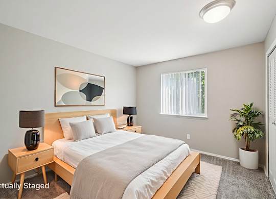 A bedroom with a bed, nightstands, and a plant.