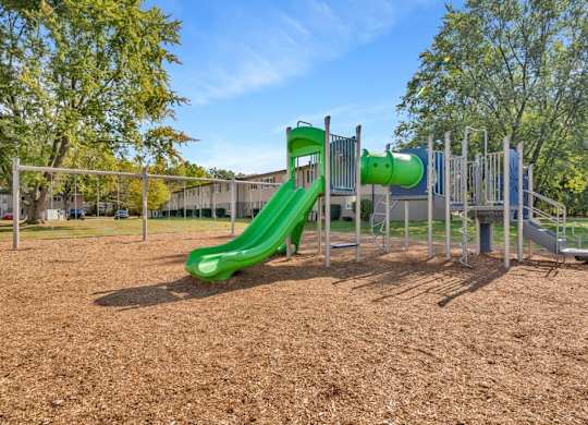 A playground with a green slide and a climbing frame.