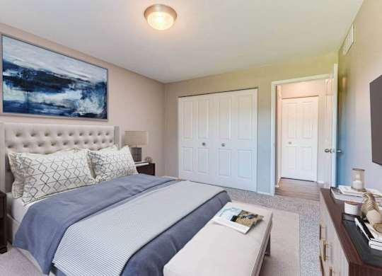 A bedroom with a large bed and a painting on the wall.