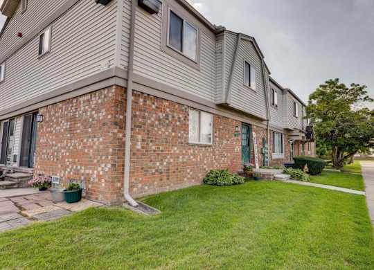 A brick house with a grey roof and a green door.