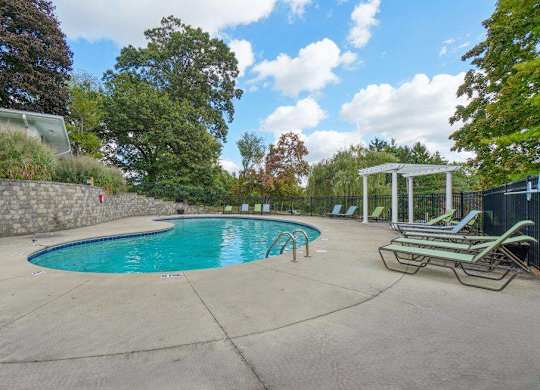 A swimming pool surrounded by trees and a stone wall.