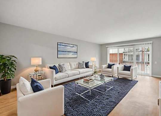 A living room with a white couch, a coffee table, and a large window.