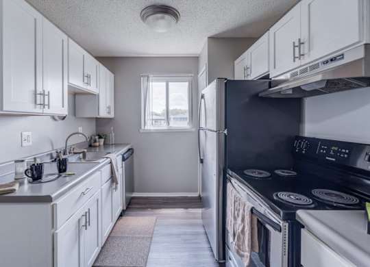 A kitchen with white cabinets and a black stove top oven.