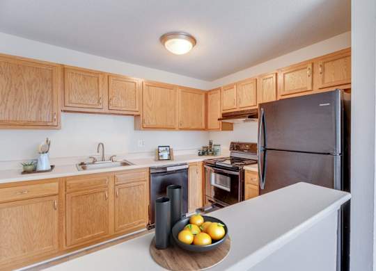 A kitchen with wooden cabinets and a black refrigerator.