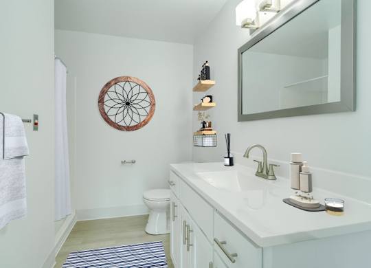 A bathroom with a white counter top and a round mirror on the wall.