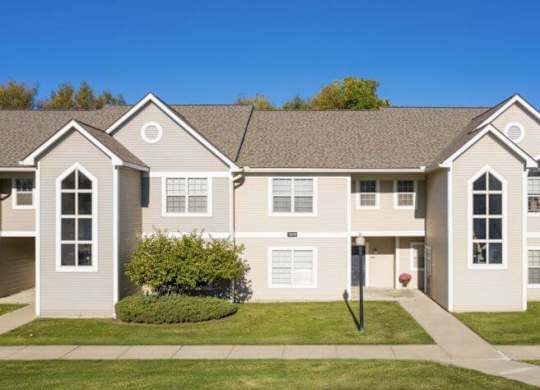 A large, two-story residential building with a lawn in front.