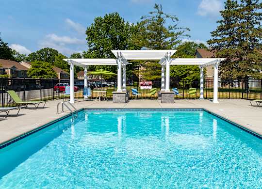 A pool with a white pergola over it.