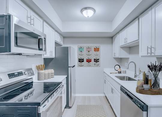 A modern kitchen with white cabinets and stainless steel appliances.