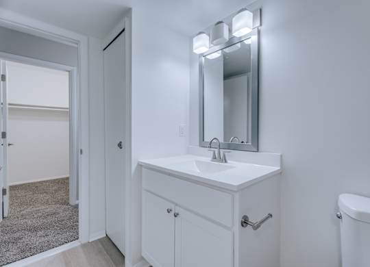 A white bathroom vanity with a mirror above it.