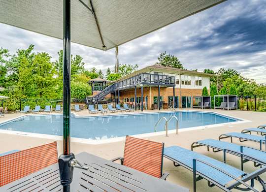 A pool with sun loungers and a building in the background.