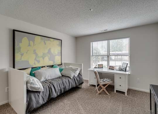 A bedroom with a bed, desk, and chair.