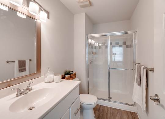 A white bathroom with a sink, toilet, and shower.