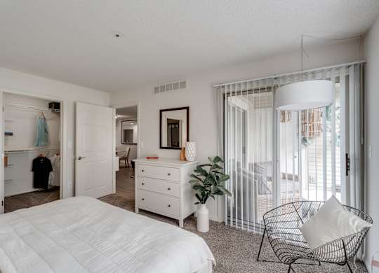 A white bedroom with a large bed and a chair.