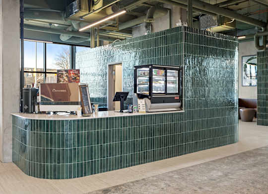 A green tiled counter with a coffee machine and a bag of coffee on it.