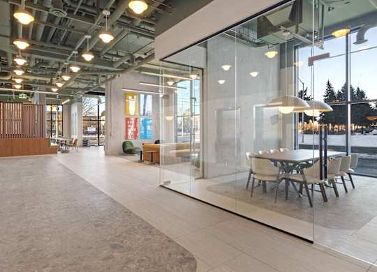 A modern office space with glass walls and a long table with chairs.