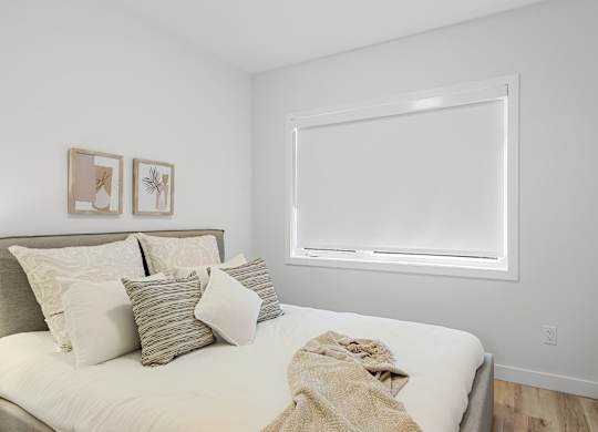 A bedroom with a bed, pillows, and pictures on the wall.