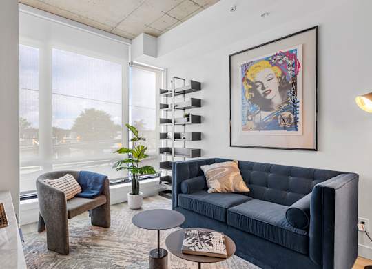 A living room with a blue couch and a framed picture of a woman.