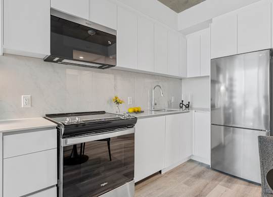 A modern kitchen with white cabinets and a stainless steel refrigerator.