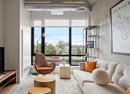 A living room with a white couch, a brown chair, and a TV.