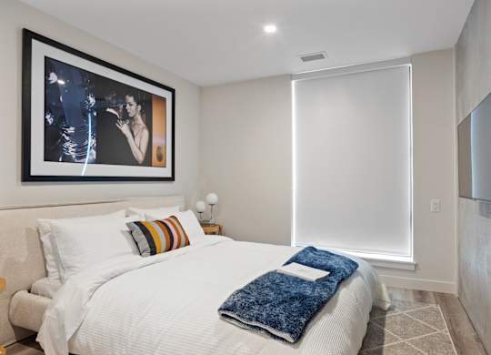 A bedroom with a large bed and a painting on the wall.