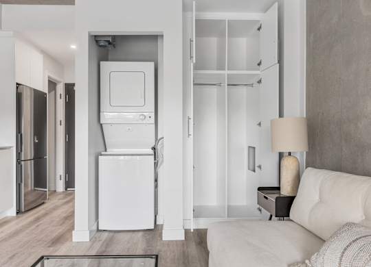 A white kitchen with a refrigerator, oven, and a white couch.
