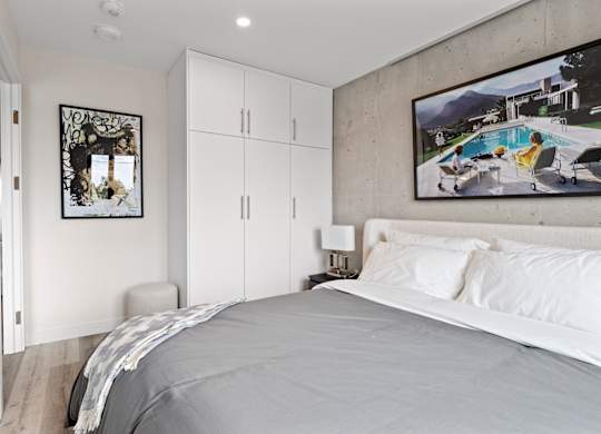 A bedroom with a large bed and a painting of a pool scene on the wall.