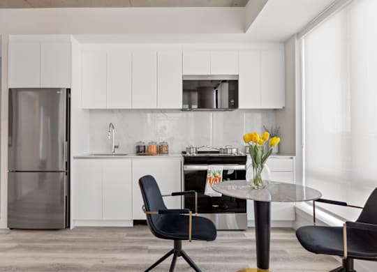 A modern kitchen with a glass table and black chairs.