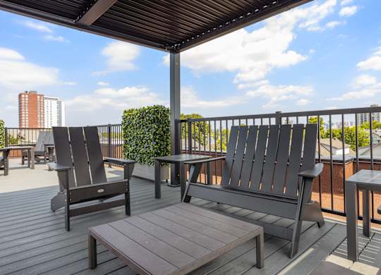 A wooden deck with a table, chairs and bench.