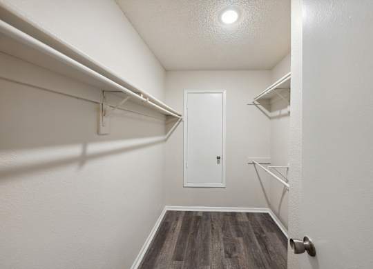 A white door is in a hallway with wood floors and white walls.