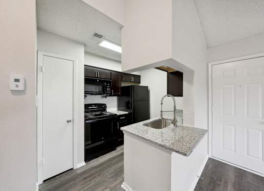 A kitchen with a granite countertop and white cabinets.