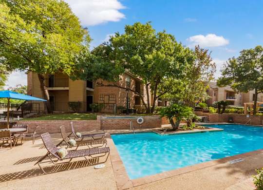 A swimming pool surrounded by trees and chairs.