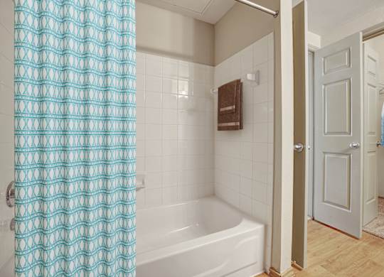 A white bathtub with a blue shower curtain in a bathroom.