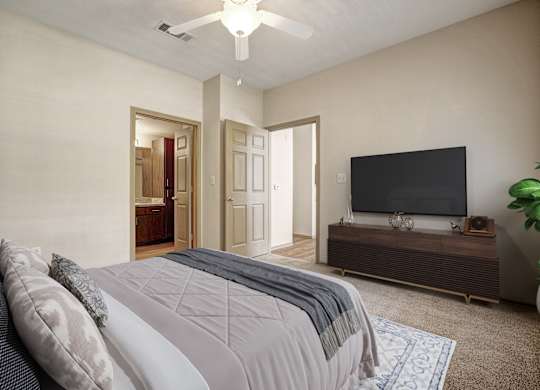 A bedroom with a bed, a television, and a plant.