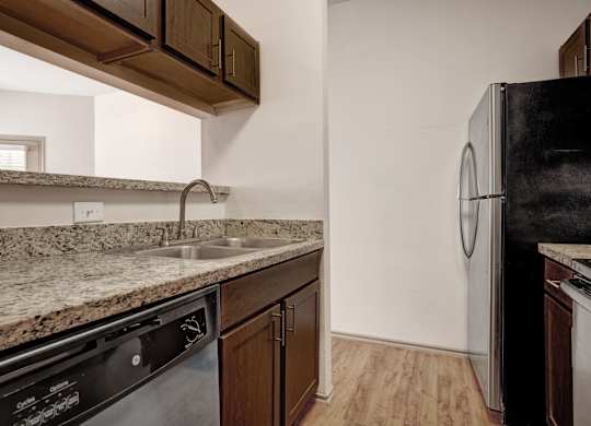 A kitchen with a black fridge and a granite counter top.