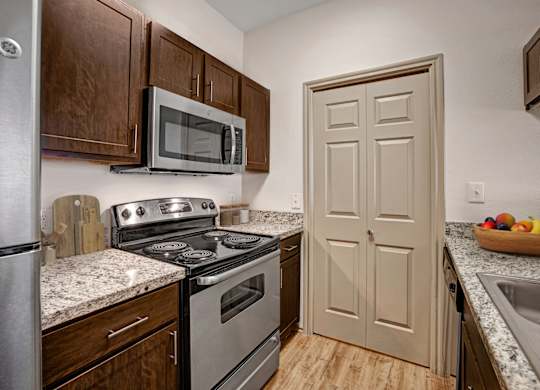 A kitchen with a stove, microwave, and oven.