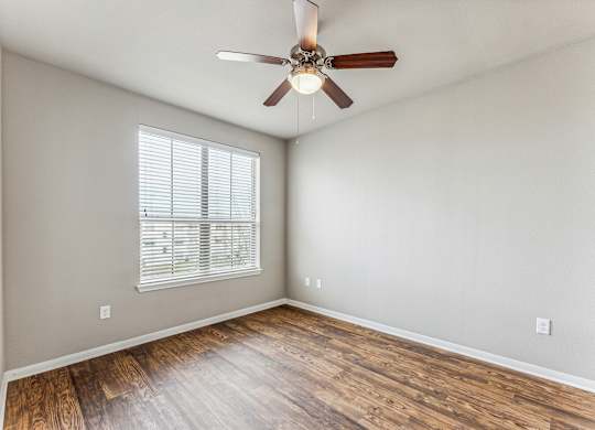 A room with a ceiling fan and wooden flooring.