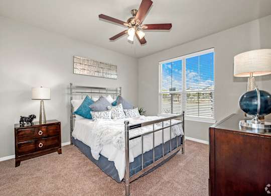 A bedroom with a bed, dresser, and ceiling fan.