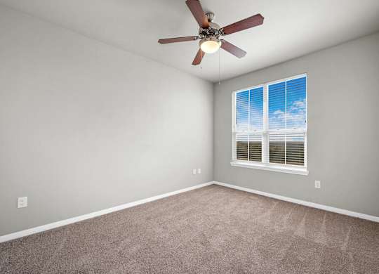A room with a ceiling fan and a window with blinds.
