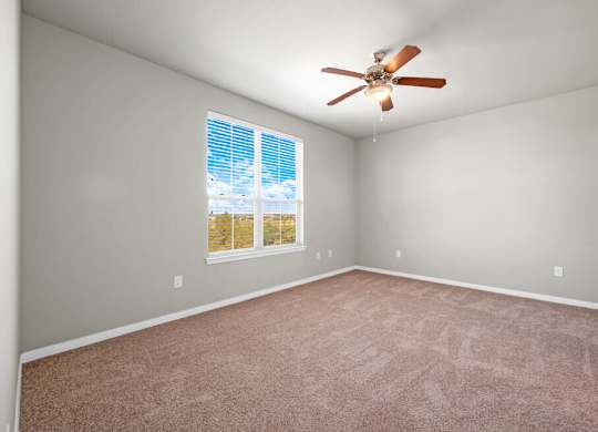 A room with a ceiling fan and a window with blinds.