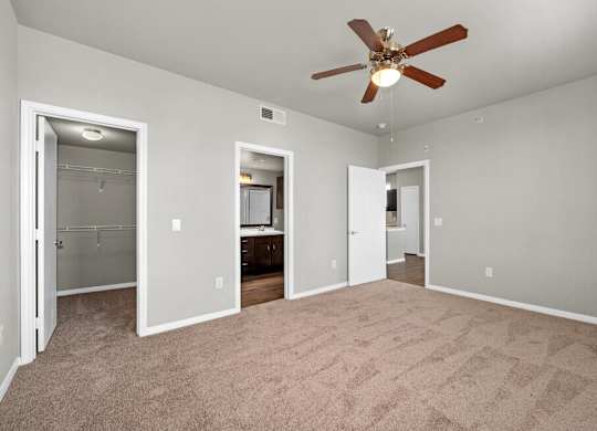 A room with a ceiling fan and carpeted floor.