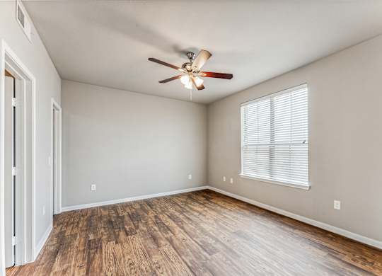 A room with a ceiling fan and wooden flooring.