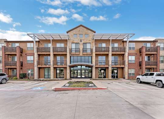A large apartment complex with a parking lot in front.