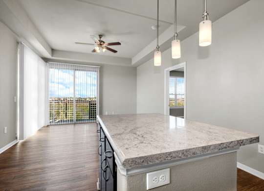 A spacious kitchen with a marble countertop and a ceiling fan.
