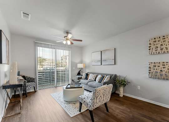A living room with a grey couch, a coffee table, and a fan.