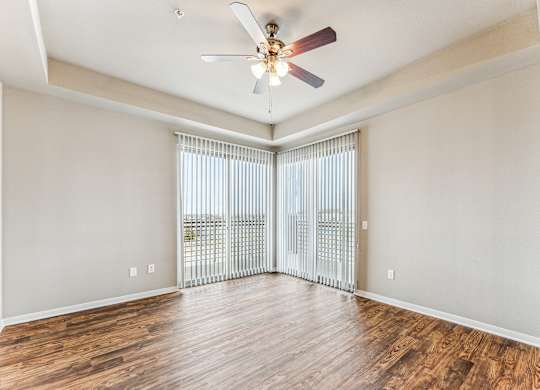 A room with a ceiling fan and sliding glass doors.