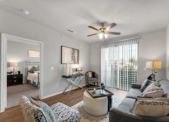 A living room with a grey couch and a ceiling fan.