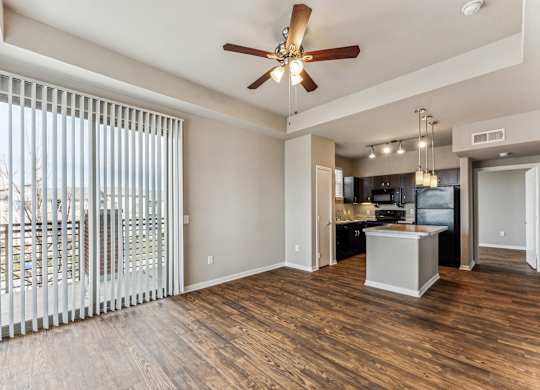 A spacious living room with a ceiling fan and sliding glass doors.