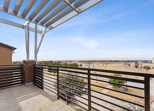 A balcony with a metal railing and a concrete floor.