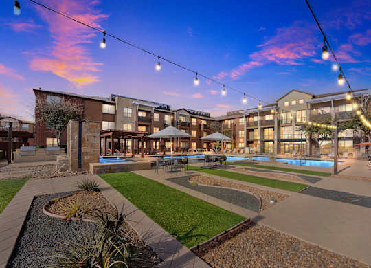 A sunset view of a courtyard with a pool and apartment buildings.