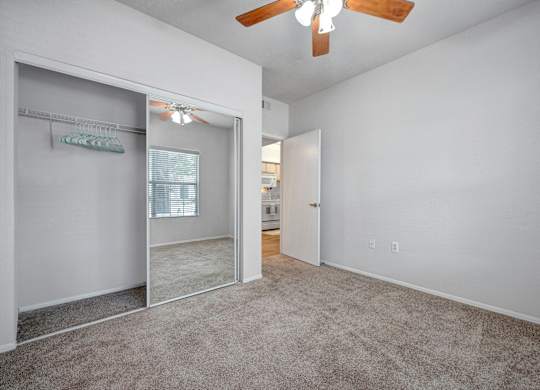 A room with a carpeted floor and a ceiling fan.